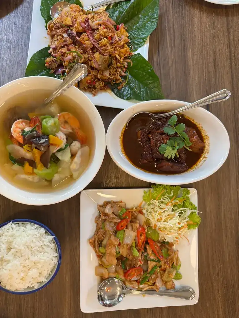 Moo hong, a soup with prawns and vegetables, a salad laid on green leaves and a stir-fry, seen from above