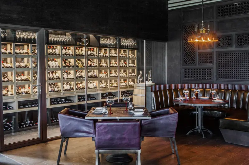 Purple leather chairs at a table beside the glass wine room / เก้าอี้หนังสีม่วงที่โต๊ะข้างห้องเก็บไวน์ผนังกระจก