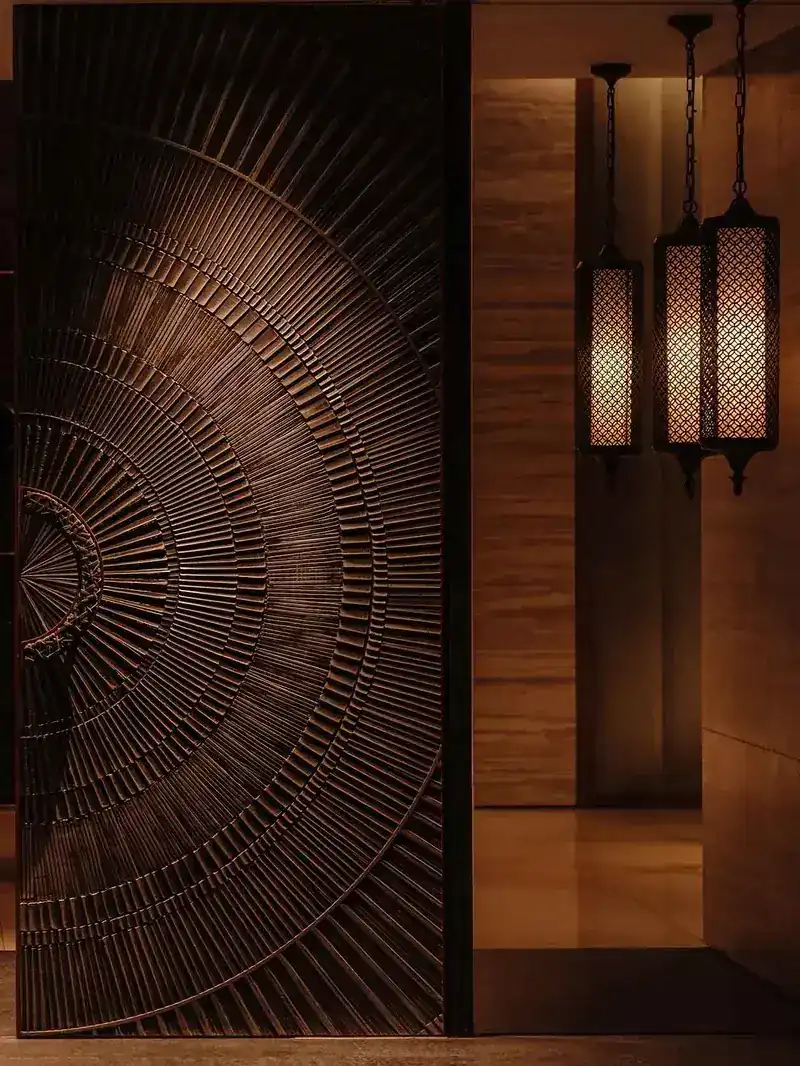 Carved fan-pattern door and hanging lanterns at the entrance
