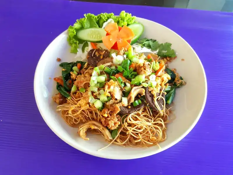 Stir-fried thin noodles with greens, mushrooms and spring onion, garnished with cucumber and carrot