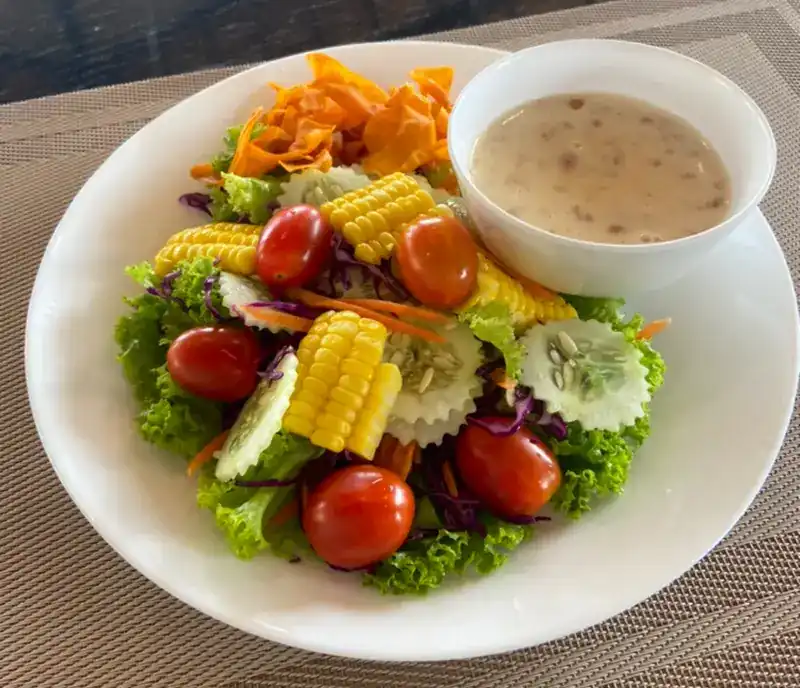 Green salad with corn, tomatoes and cucumber, dressing on the side