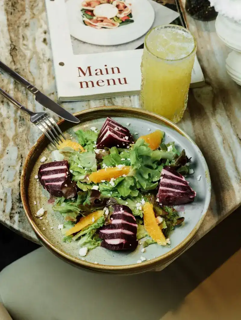 Beet and orange salad with feta, a glass of juice beside it