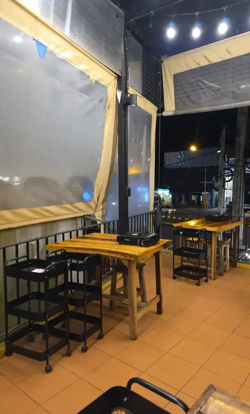 The covered upstairs terrace with wooden tables, gas burners and clear roll-down sides
