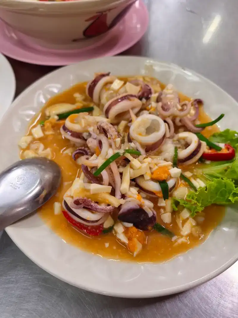 Squid rings in an orange sauce with chilli, spring onion and lettuce