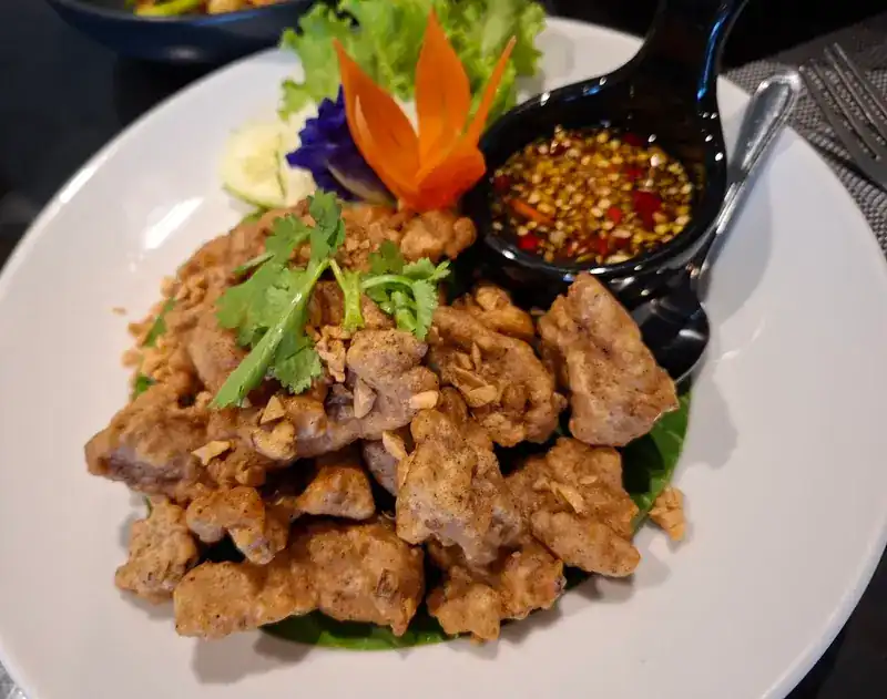 Fried pork topped with crisp garlic and coriander, a chilli dip and a carved carrot