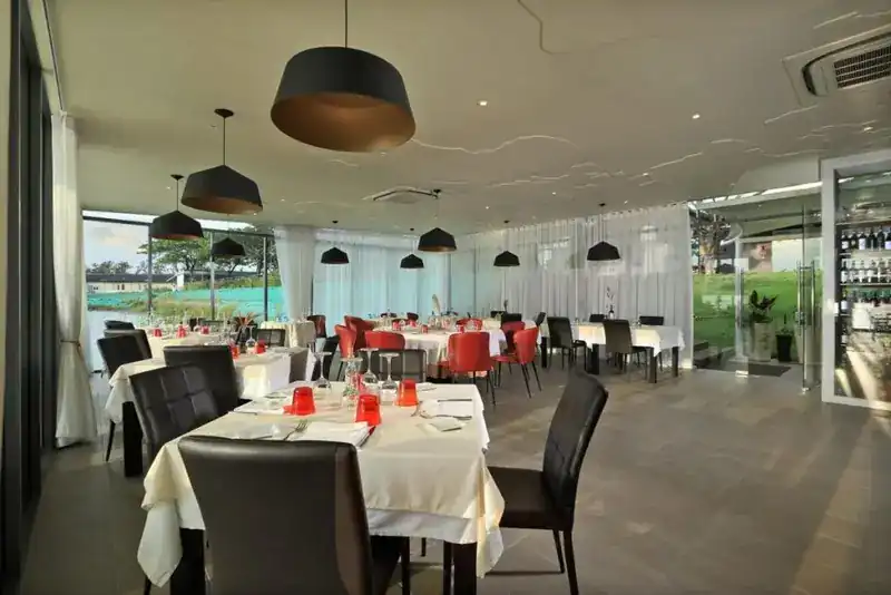 The dining room: white tablecloths, dark chairs and black pendant lamps, glass walls all round