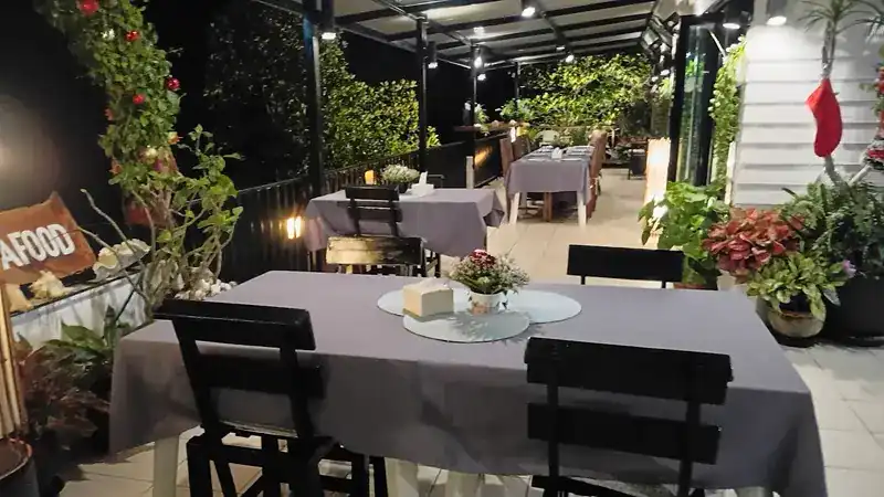 A garden corner of the deck in the evening, tables in lilac cloth under the lights