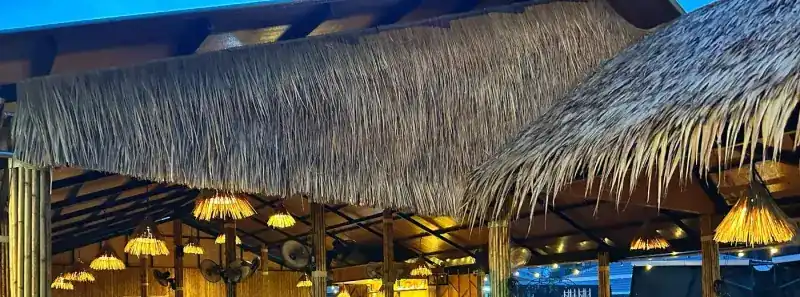 Woven lamps glowing under the thatch at blue hour