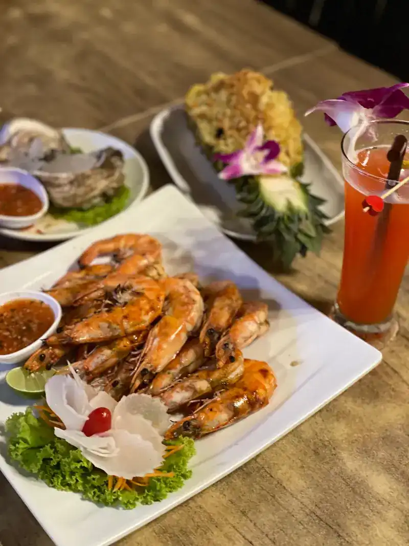 A plate of prawns with chilli sauce, oysters, and rice served in a pineapple