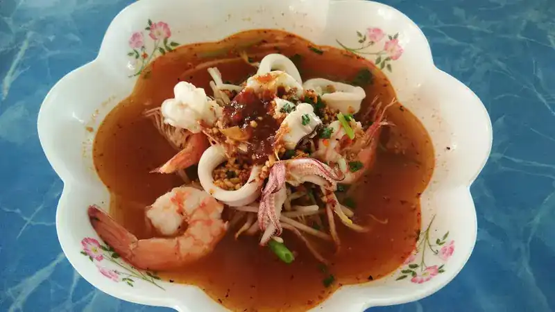Red, spicy soup with prawns, squid and bean sprouts in a flower-shaped bowl