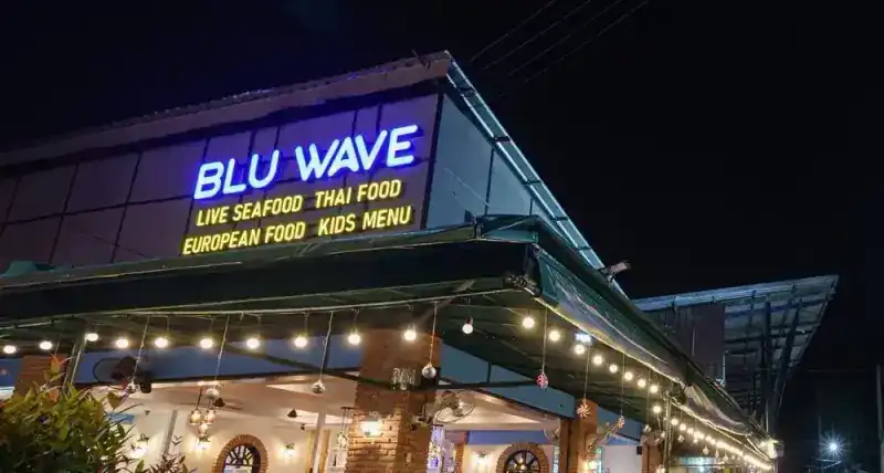 The restaurant at night, with its blue neon sign above the terrace lights
