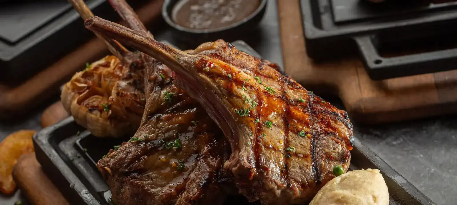 Grilled lamb chops with char marks on a black iron plate