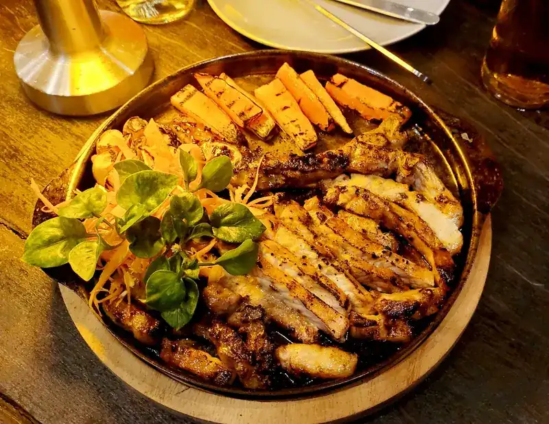 Sliced grilled meat and grilled vegetables on a hot iron plate