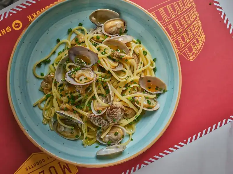 Spaghetti with clams on a pale blue plate