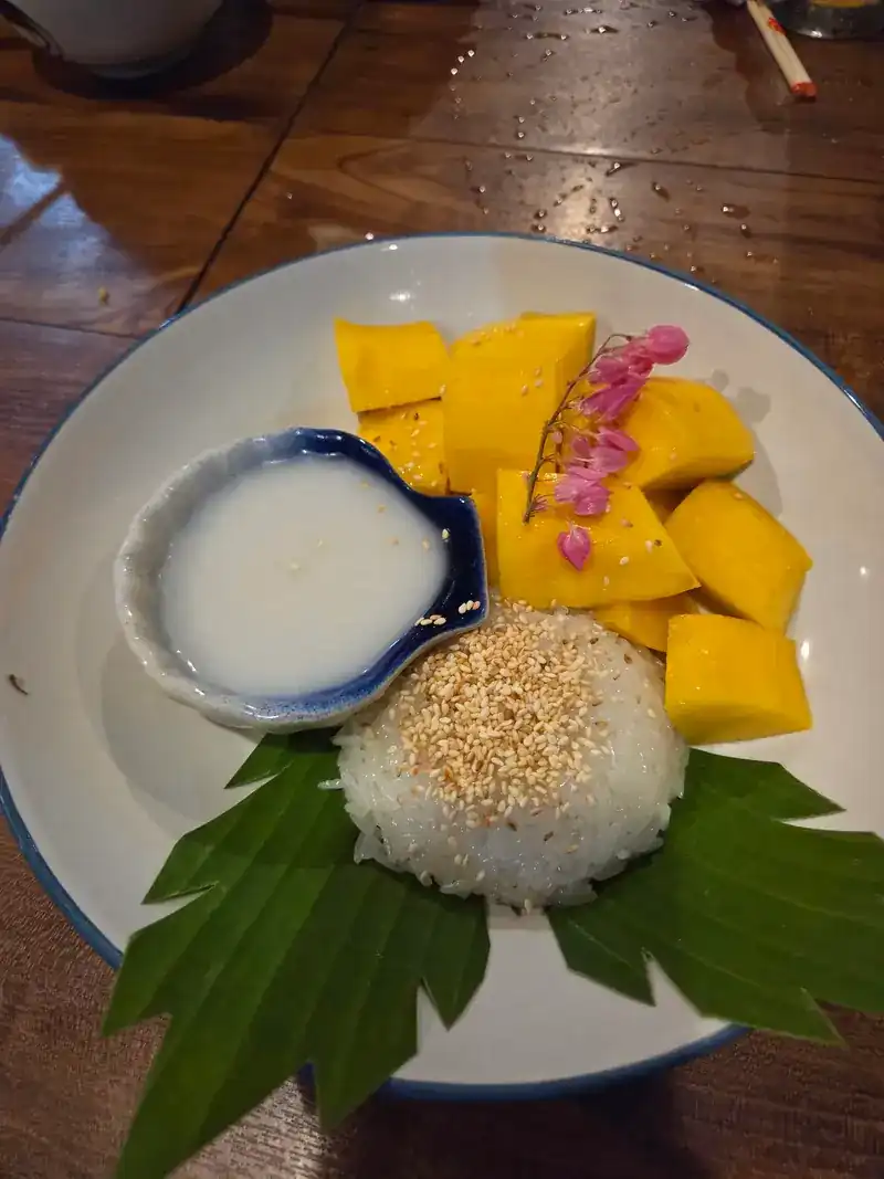 Mango with sticky rice, coconut cream and sesame, with pink flowers