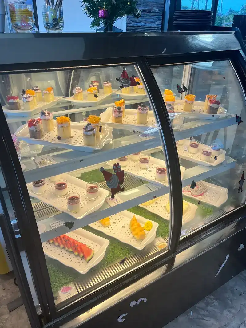 The dessert cabinet with panna cotta, small cakes and cut fruit