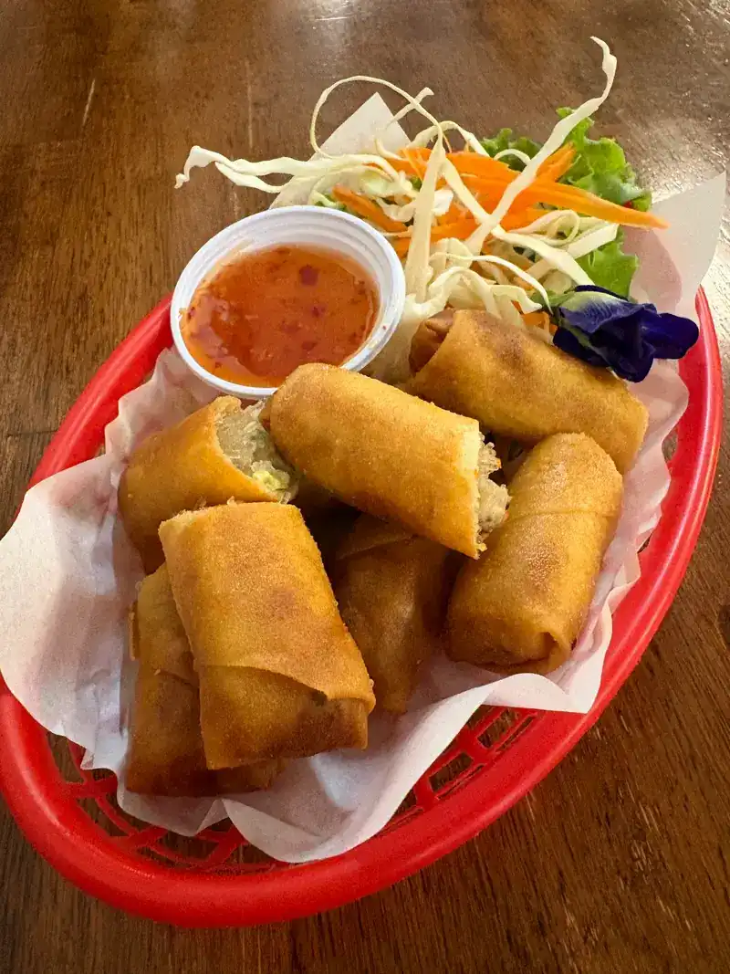 Spring rolls in a red basket with a dipping sauce