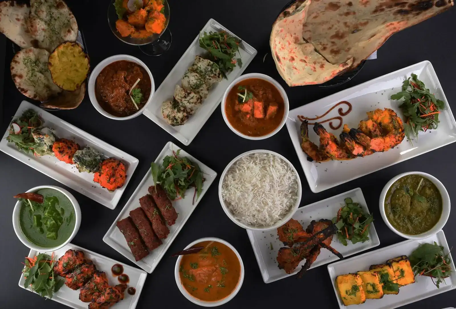 A table seen from above: curries, tandoori grills, rice and naan at Highway Curry