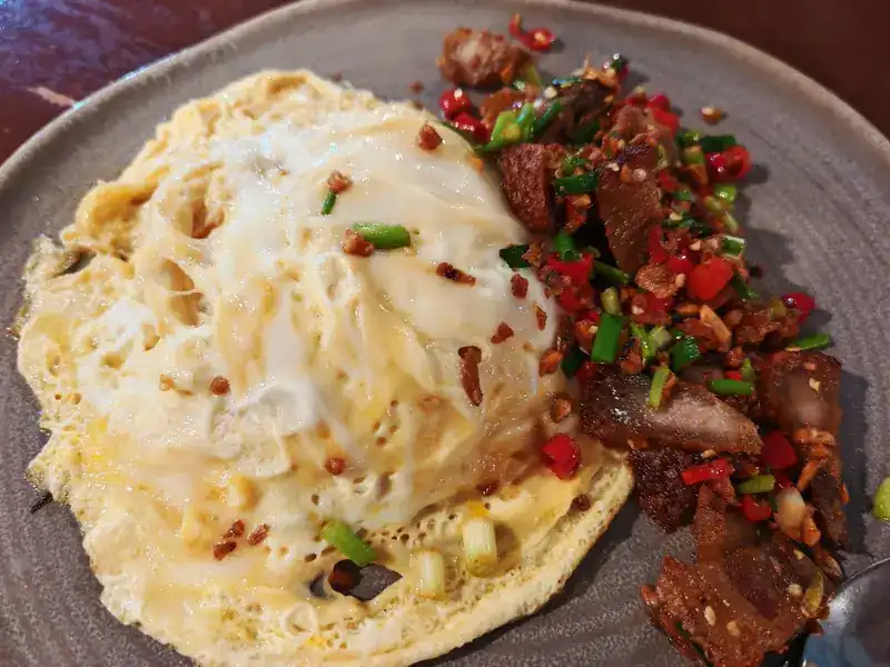 Crispy pork tossed with chilli and spring onion, with a fried egg