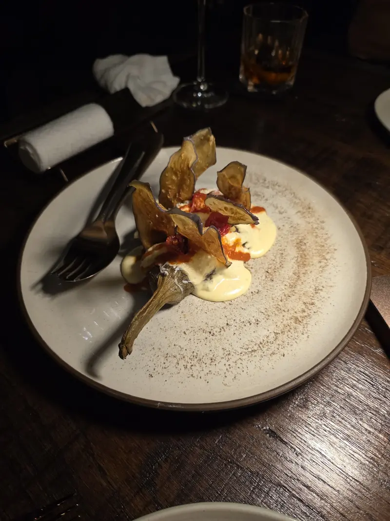 Artichoke with crisps and a pale sauce on a white plate / อาร์ติโชกกับแผ่นกรอบและซอสครีมบนจานขาว