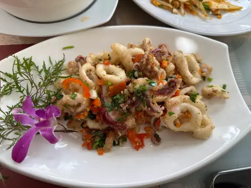 Squid rings with chopped chilli and herbs, an orchid on the plate