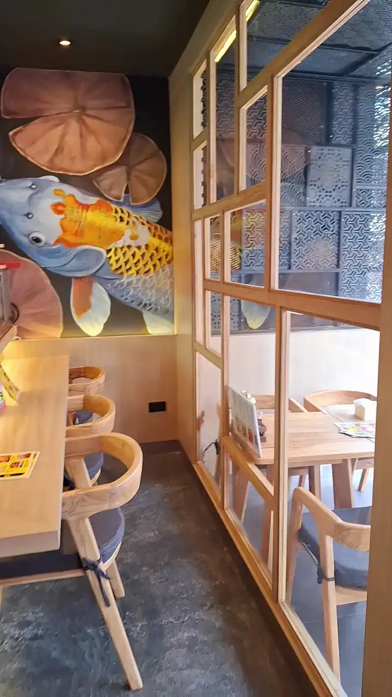 Koi mural beside wooden window screens and dining chairs