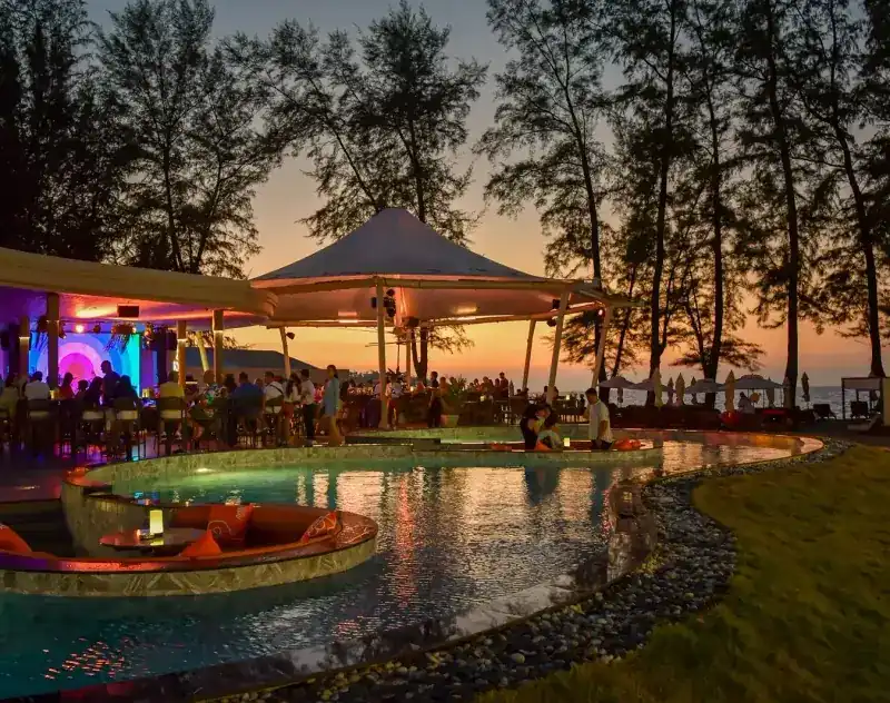 The pool and its round sunken seat lit up at sunset, with the open-air pavilion behind