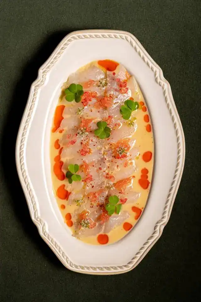 Madai ceviche with spicy oil on a white oval plate