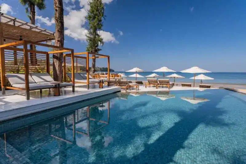 Pool salas and white parasols lined up along the beach