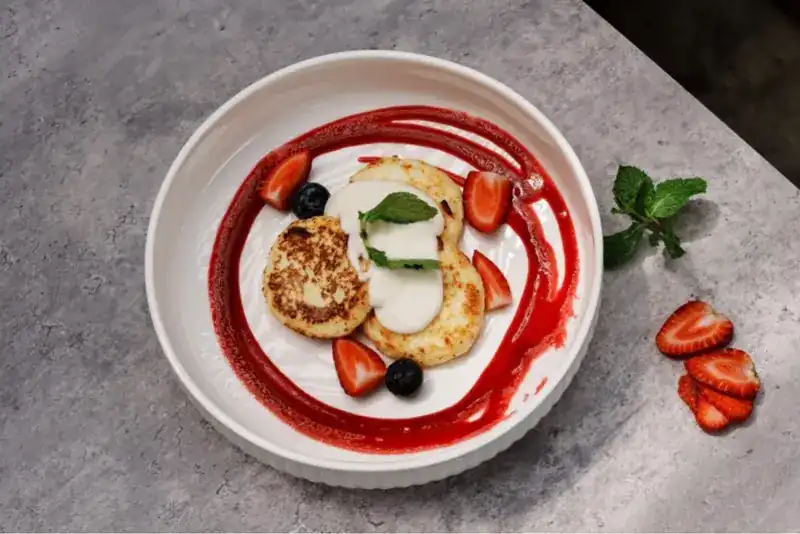 Syrniki with sour cream, strawberries and raspberry jam
