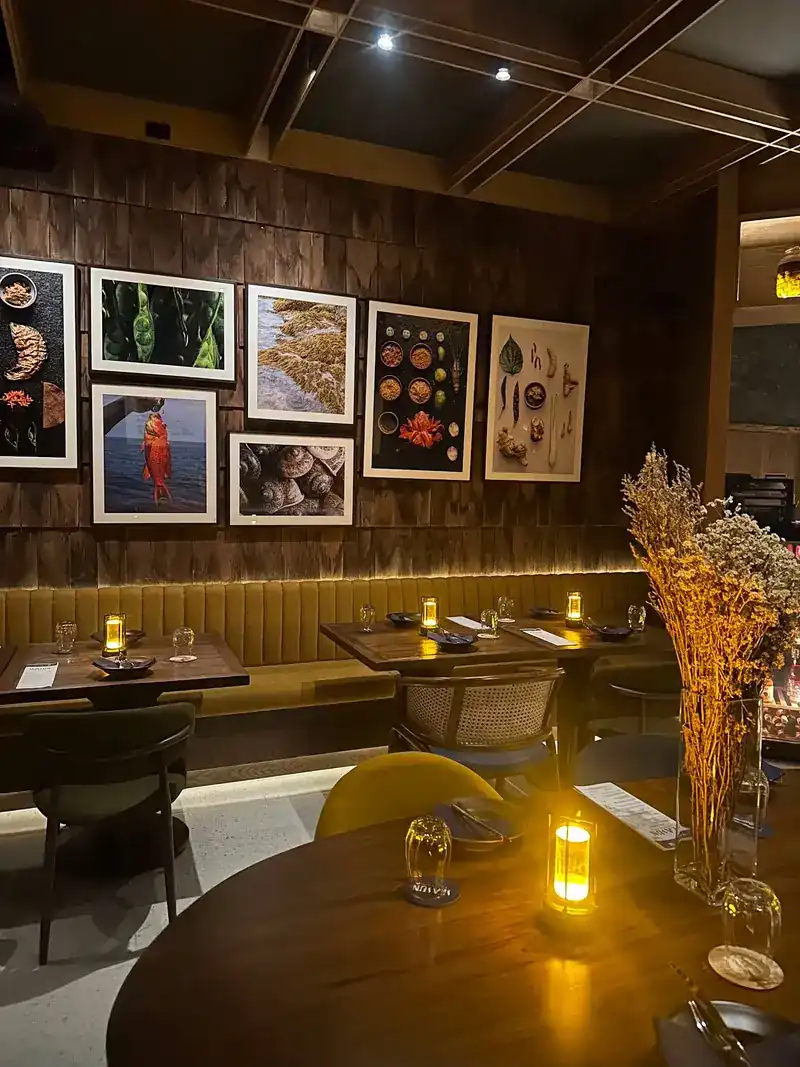 The dining room: candlelit tables, a long banquette and framed pictures on a wood-panelled wall