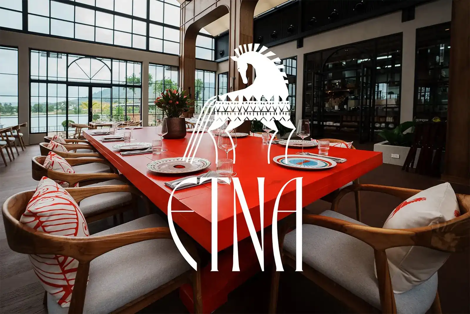 The long red table in the main hall of ETNA, with the lake behind the glass