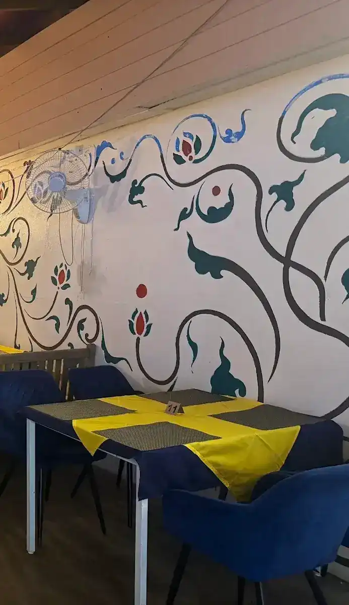 Inside: a table with a yellow cloth over navy, in front of the painted vine wall