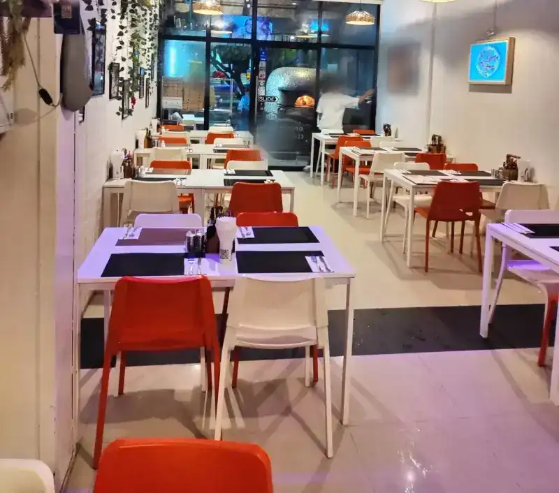 The dining room: white tables, red and white chairs, and the oven seen through the front glass