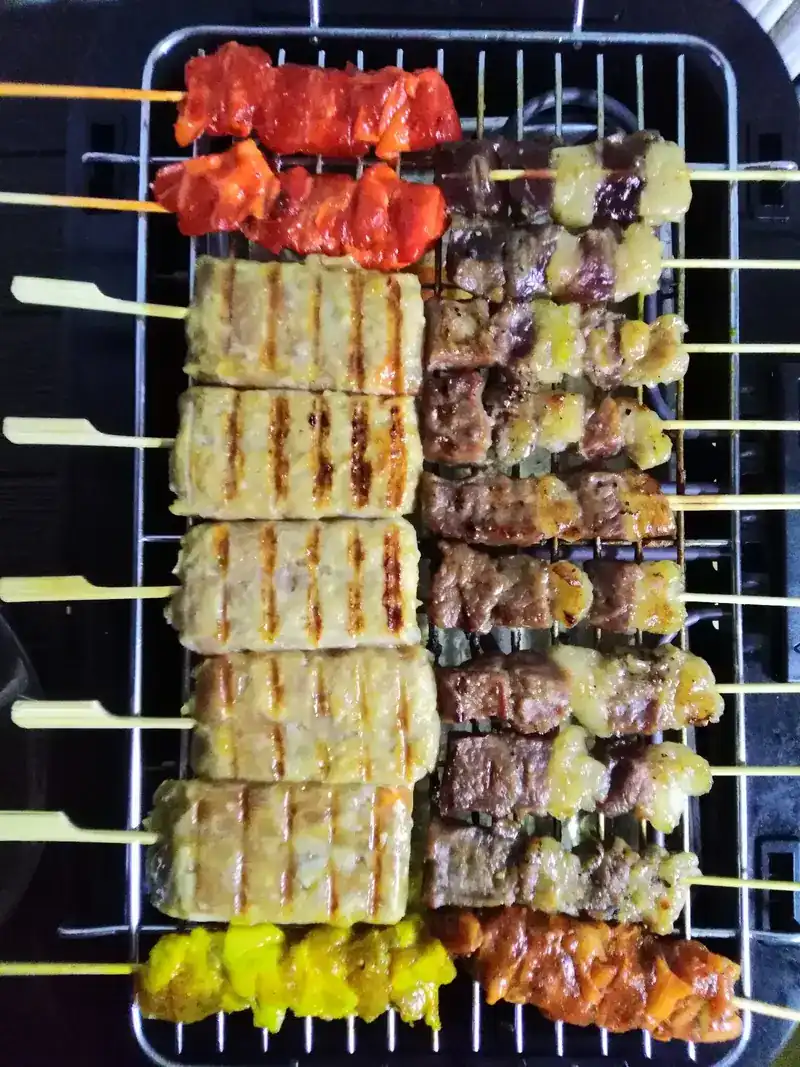 Skewers lined up on a grill rack, some with grill marks