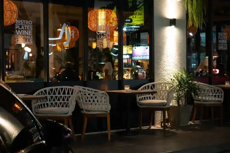 Woven chairs and candle-lit tables on the terrace at night