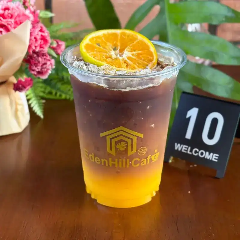 Iced coffee over orange juice, topped with an orange slice. กาแฟเย็นบนน้ำส้ม แต่งด้วยส้มฝาน