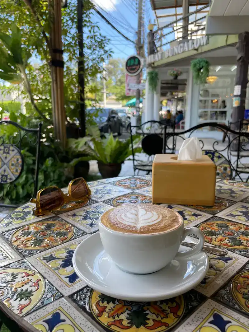 Cappuccino with latte art on a hand-painted tile table outside the café