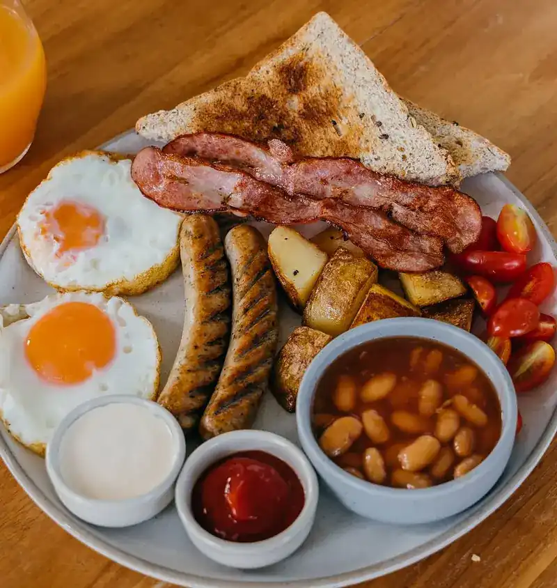 English breakfast with fried eggs, sausages, bacon, potatoes, beans and toast