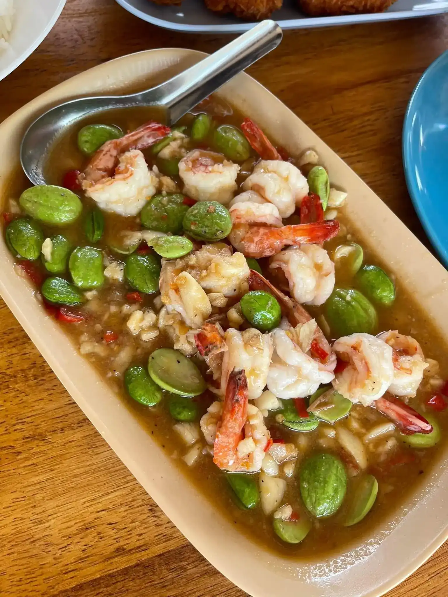 Prawns and stink beans in a chilli sauce, on a wooden table