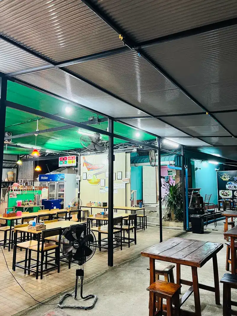Wooden tables and stools under the roof with the lights on in the evening