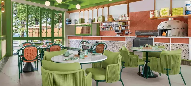 The dining room: green rattan chairs, terrazzo counter and the wood-fired oven