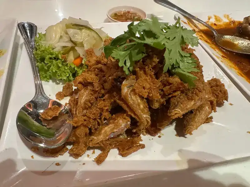 A crisp-fried dish topped with coriander, served with pickles and lettuce
