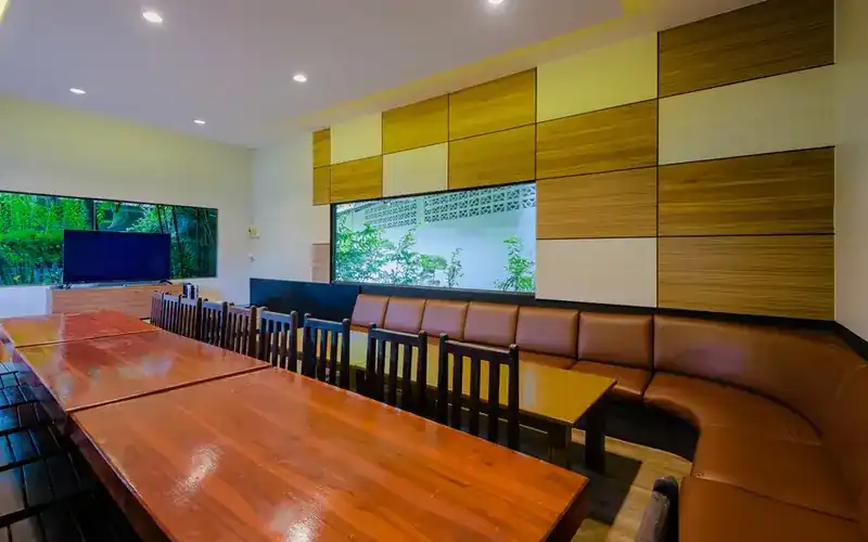 A karaoke room set with long wooden tables for a large group