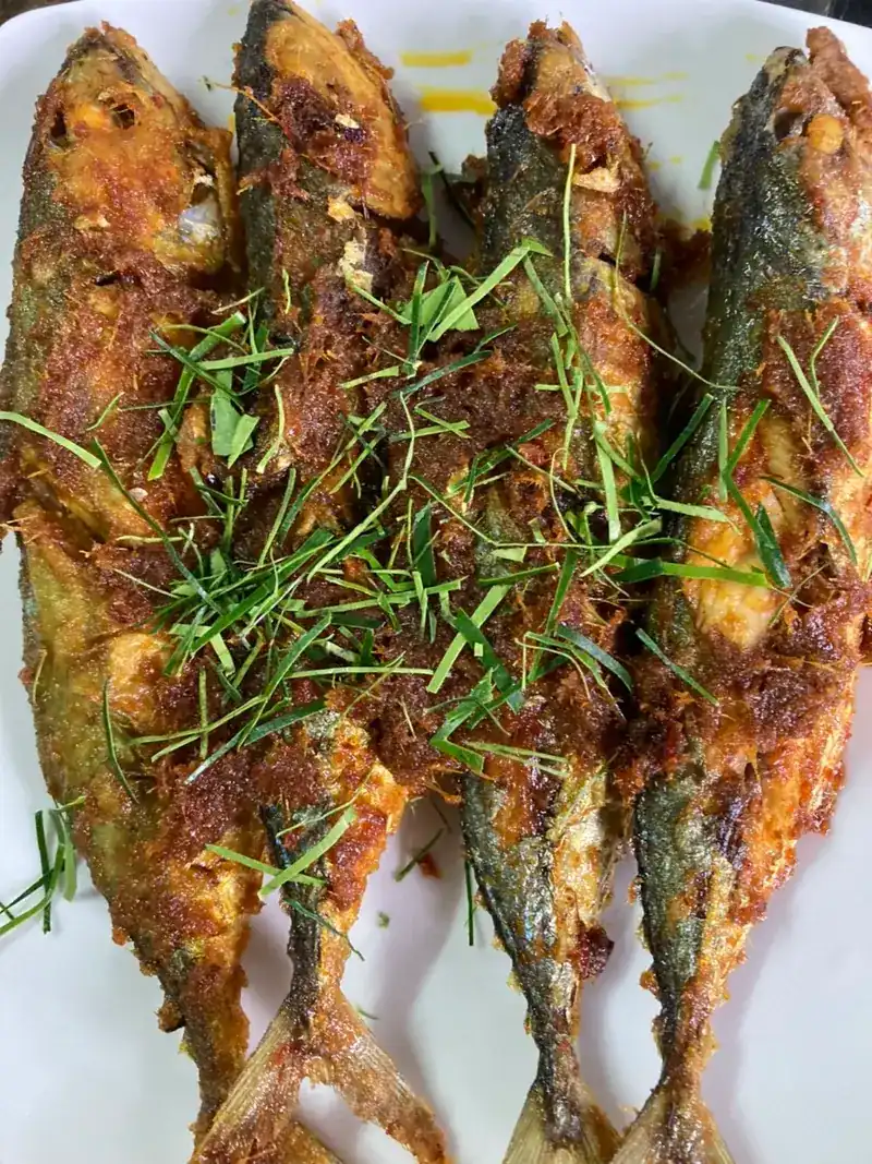 Fried fish coated in a red spice paste, with fine-cut herbs on top