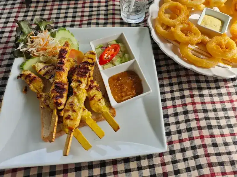 Grilled satay skewers on toast with peanut sauce and cucumber relish