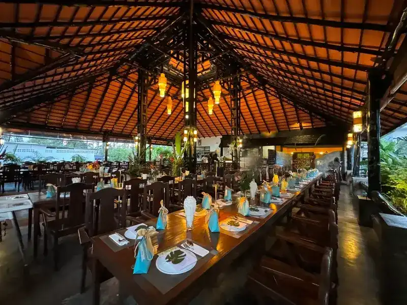 A long table laid for a group with turquoise napkins, under the tiled roof