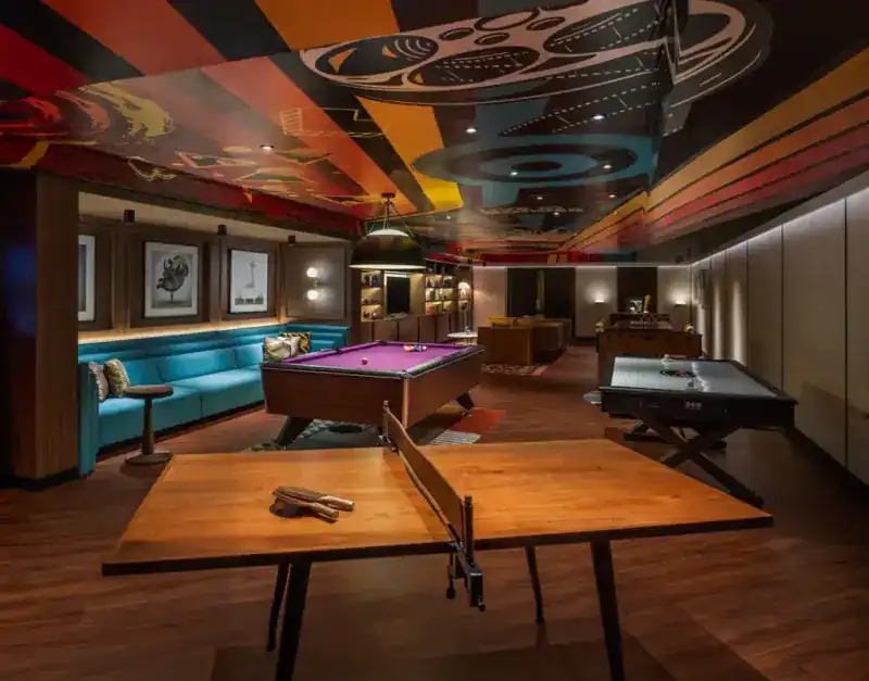 The Den: a teal sofa, a pool table and a table tennis table under a painted ceiling