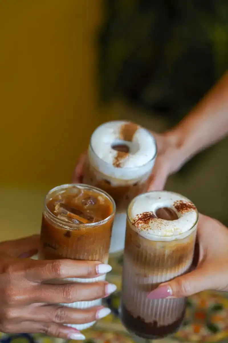 Three iced coffees in ribbed glasses held up together