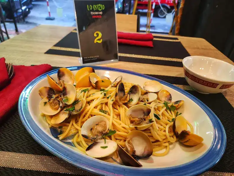 Spaghetti with clams on a blue-rimmed plate
